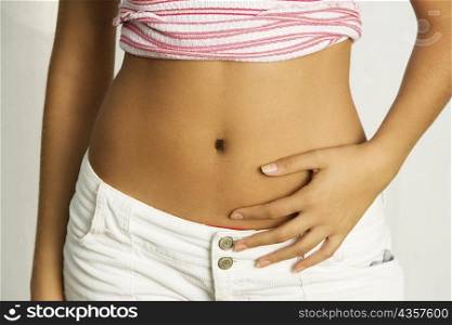 Mid section view of a young woman with her hands on her stomach