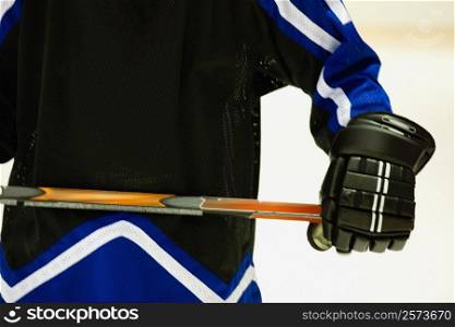 Mid section view of an ice hockey player holding an ice hockey stick