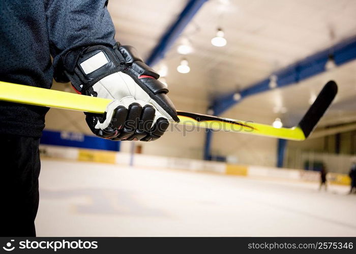 Mid section view of an ice hockey player holding an ice hockey stick