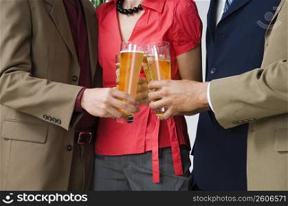 Mid section view of four business executives toasting with glasses of beer