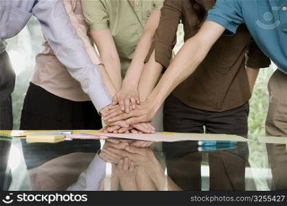 Mid section view of office workers stacking hands on a table