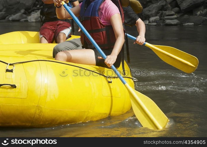 Mid section view of three people rafting in a river