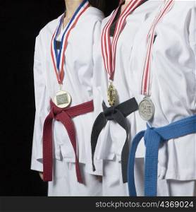 Mid section view of three people standing with their medals