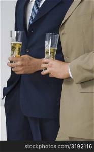 Mid section view of two businessmen holding glasses of beer in a party