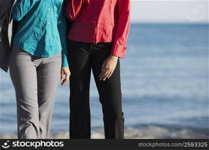 Mid section view of two women standing on the beach