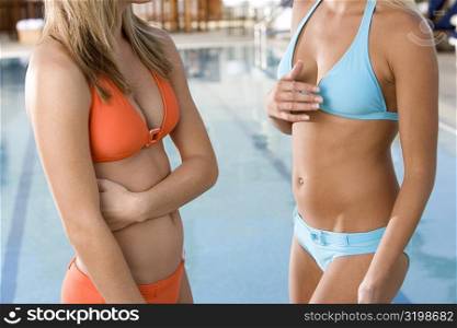 Mid section view of two young women standing at the poolside