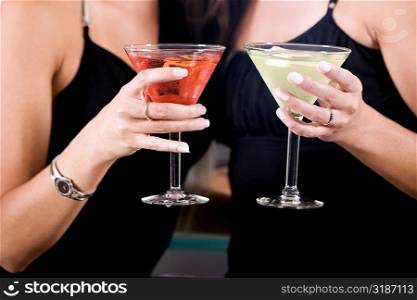 Mid section view of two young women toasting martinis