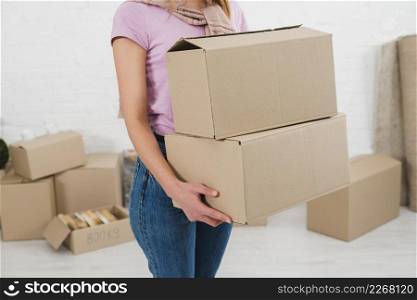mid section young woman holding stack cardboard boxes
