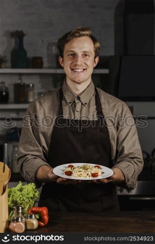 mid shot chef holding plate with pasta