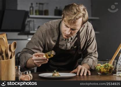 mid shot chef plating dish with oil