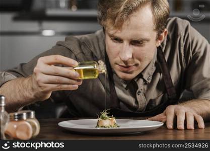 mid shot chef plating dish with olive oil