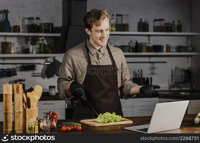 mid shot chef with salad looking laptop