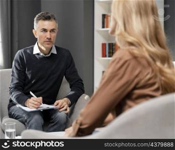 mid shot counselor with clipboard looking woman