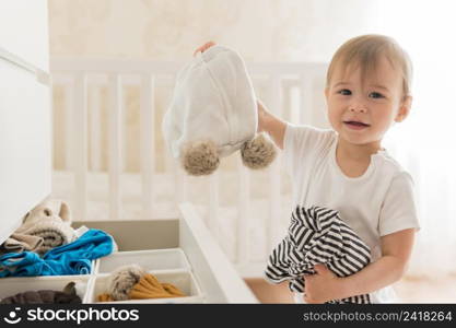 mid shot cute baby taking clothes from drawer