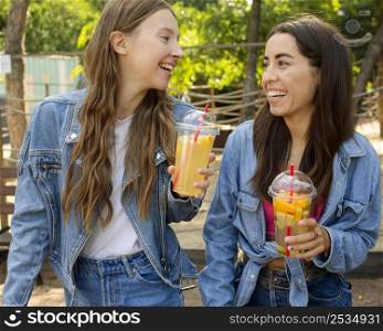 mid shot friends holding fresh juice laughing
