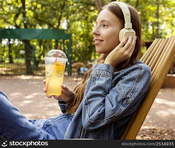 mid shot girl with headphones drinking fresh juice