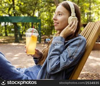 mid shot girl with headphones drinking fresh juice