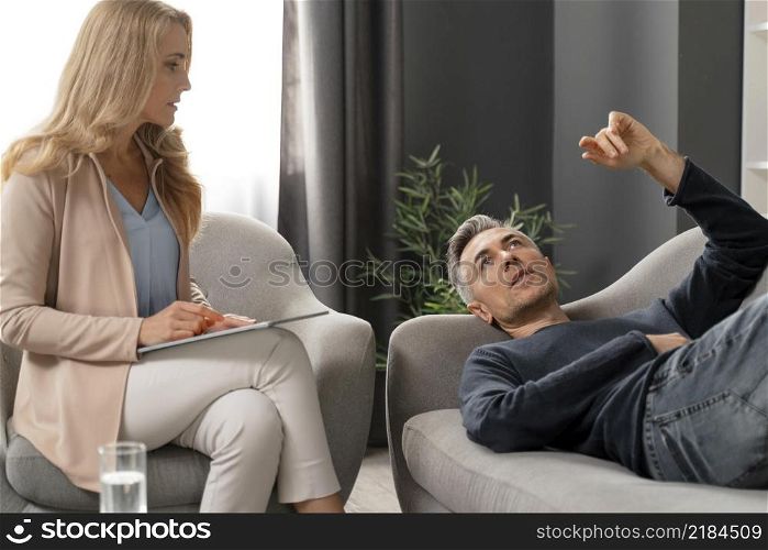 mid shot man laying couch therapy cabinet near counselor