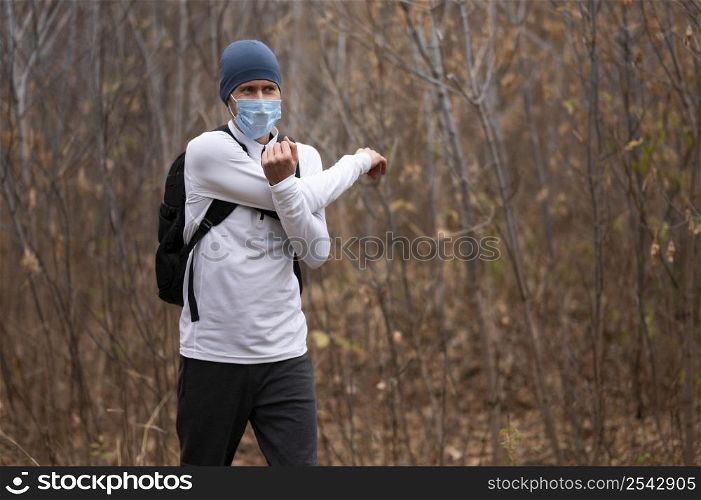 mid shot man with face mask woods stretching arms