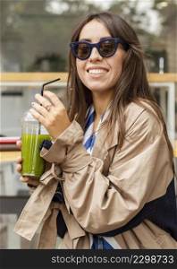 mid shot woman drinking green smoothie