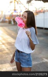 mid shot woman eating pink cotton candy