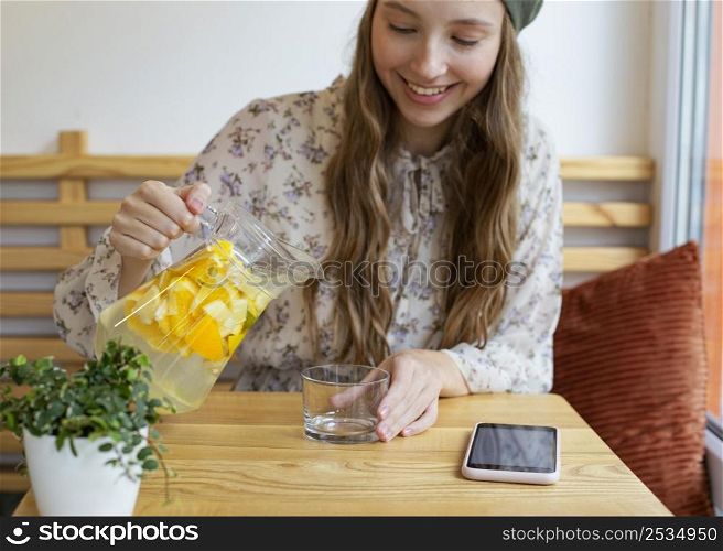 mid shot woman sitting table pouring lemonade