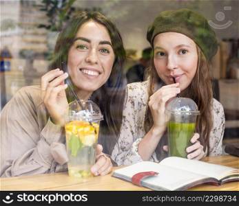 mid shot women drinking fresh juices cafe