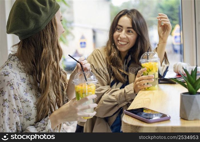 mid shot women with fresh drinks talking cafe