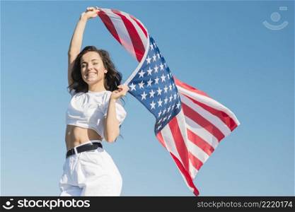 mid shot young woman holding big usa flag smiling
