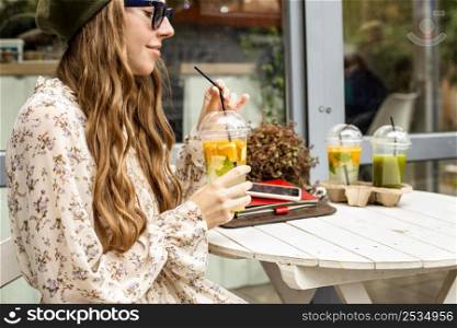 mid shot young woman holding fresh drink sitting table