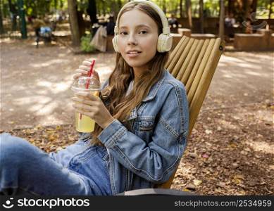 mid shot young woman with headphones holding fresh juice