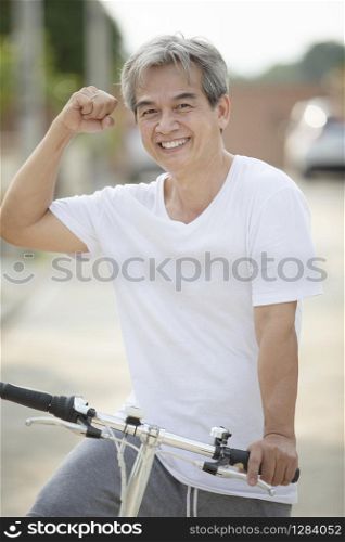 middle age asian man toothy smiling face happiness emotion exercise by riding bicycle in home village street