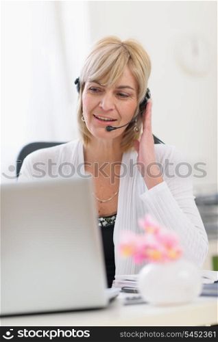 Middle age business woman with headset working on laptop