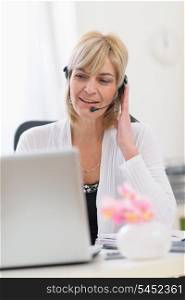 Middle age business woman with headset working on laptop