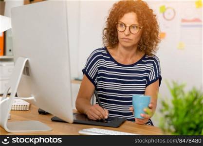 Middle age designer working on a desktop with a stylus pen
