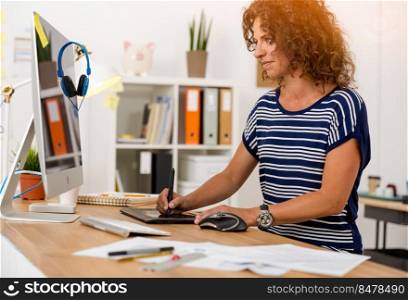 Middle age designer working on a desktop with a stylus pen