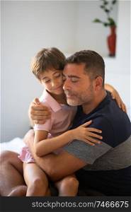 Middle-age father and her little daughter are hugging on the bed. Man spending free time with her daughter.. Middle-age man and her little daughter are hugging.