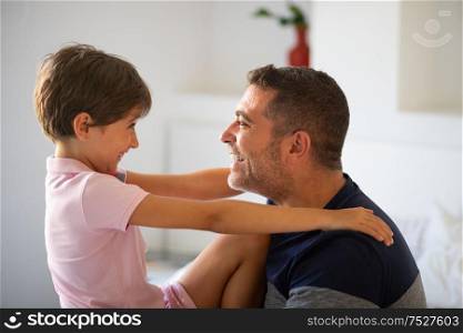 Middle-age father and her little daughter having fun at home. Man spending free time with her daughter.. Middle-age man and her little daughter are hugging.
