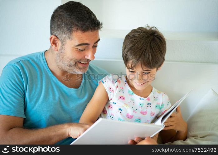 Middle-age father with her eight years daughter using digital tablet in bedroom. Funny dad and lovely little girl are having fun on the bed.. Middle-age father with her eight years daughter using digital tablet in bedroom.