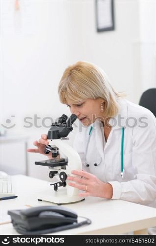 Middle age female researcher looking in microscope