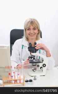 Middle age female researcher working with microscope