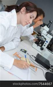 middle-age female scientist or tech writes report in modern laboratory