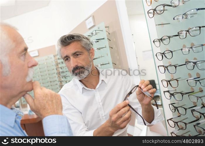 middle-age male ophthalmologist helping customer to choose glasses