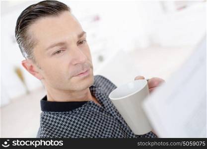 middle-age man with tablet pc computer drinking tea at home