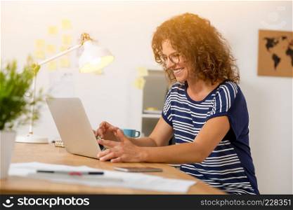 Middle age woman at the office working with a  laptop
