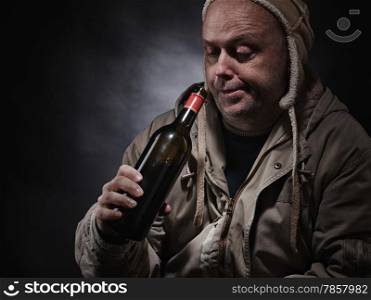 Middle aged alcoholic and wine bottle, he wearing winter clothings - focus on bottle and horizon format