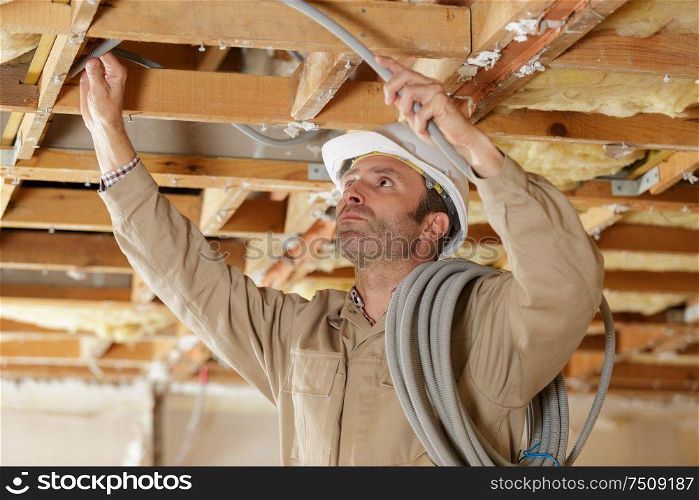 middle-aged builder installing cables on worksite