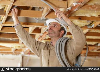 middle-aged builder installing cables on worksite