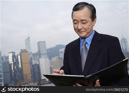 Middle-aged business man with documents, office building in background