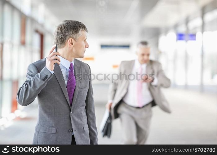 Middle aged businessman looking at colleague running in railroad station